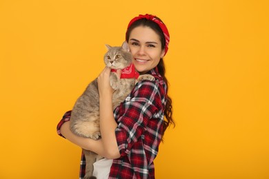 Photo of Young woman with adorable cat on yellow background, space for text