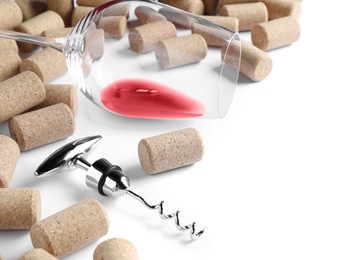 Photo of Corkscrew, glass with red wine and stoppers on white background