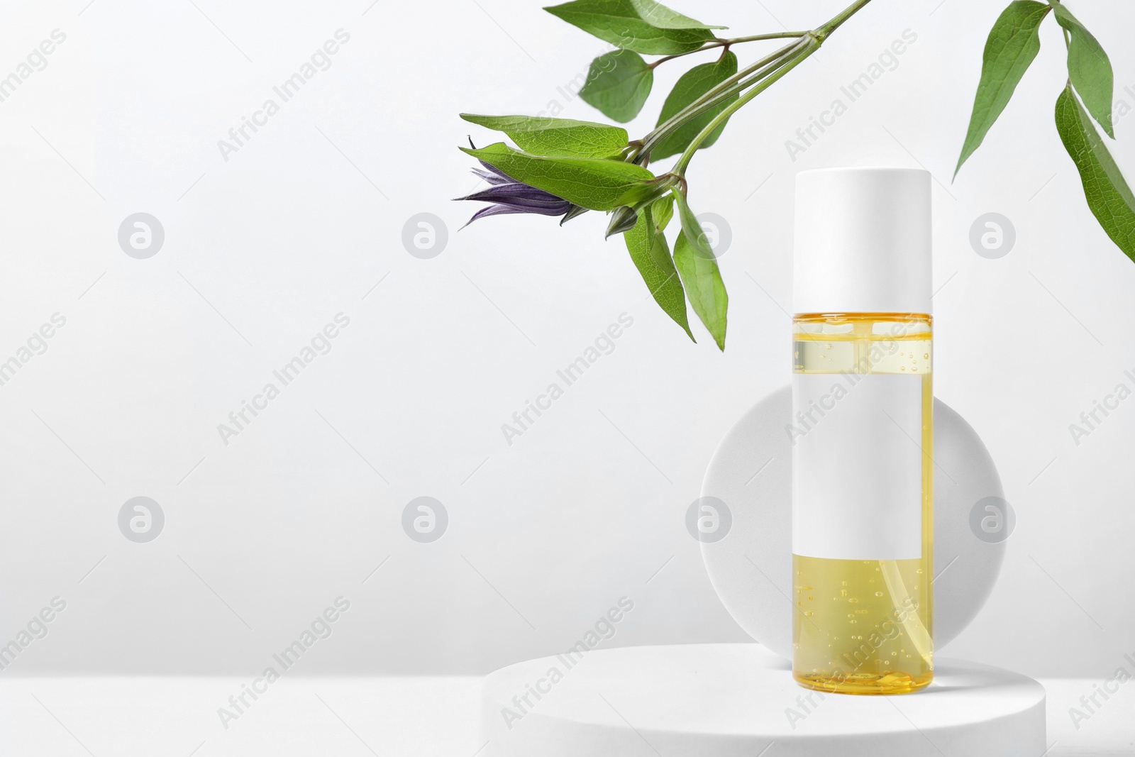 Photo of Bottle of cosmetic product and leaves on white wooden table. Space for text