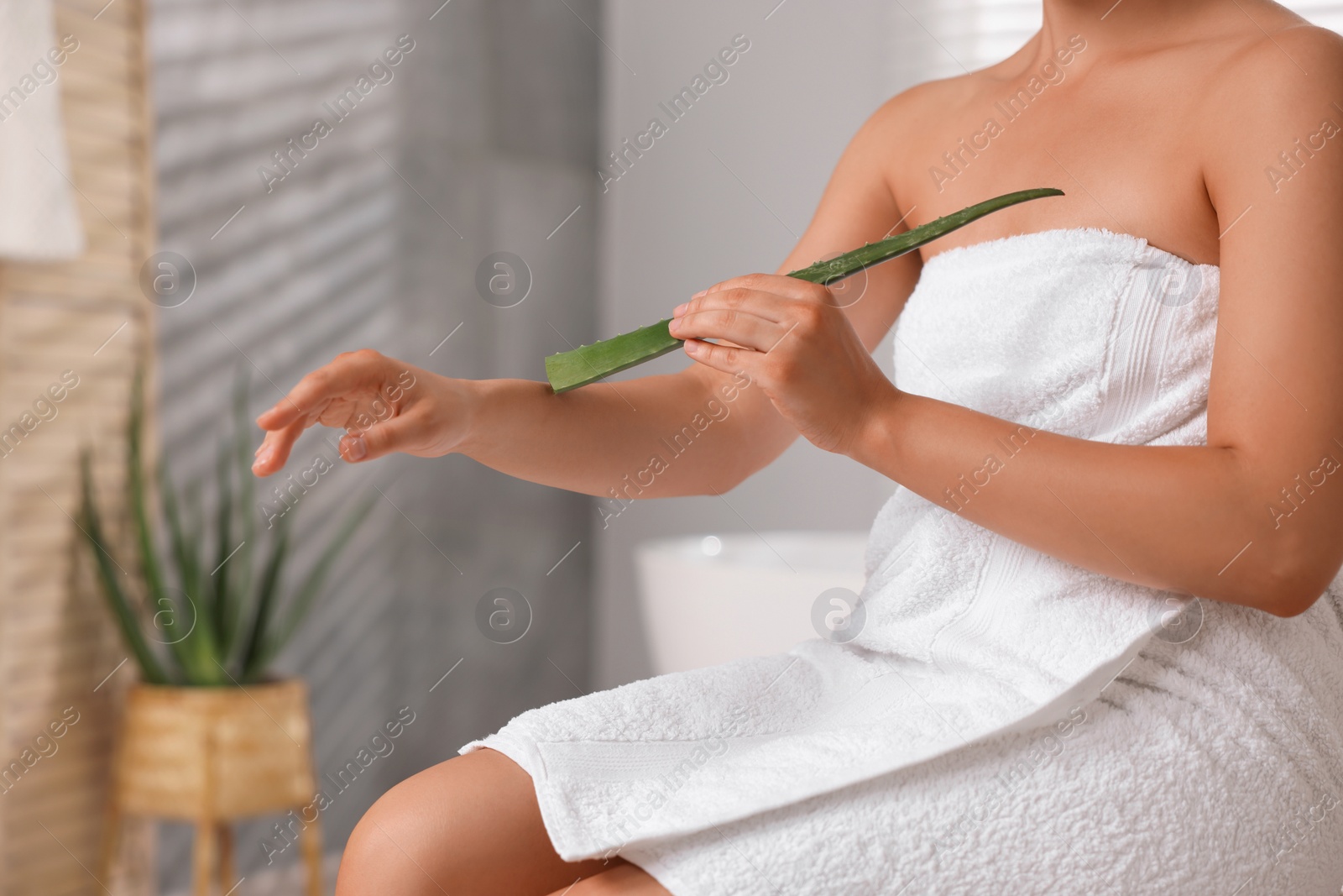 Photo of Young woman applying aloe gel onto her arm in bathroom, closeup