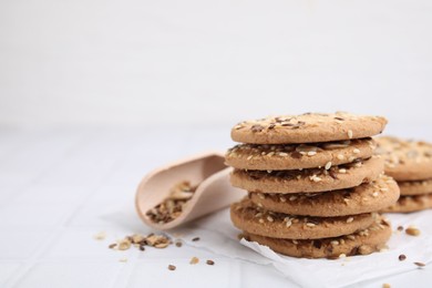 Photo of Cereal crackers with flax and sesame seeds on white tiled table, closeup. Space for text