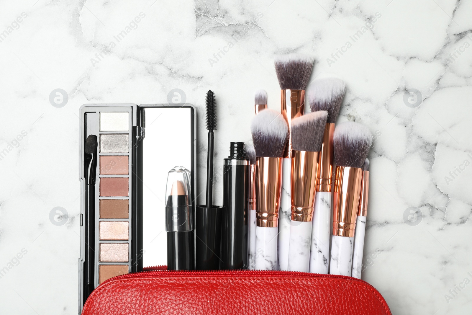 Photo of Cosmetic bag with makeup products and beauty accessories on white marble background, flat lay