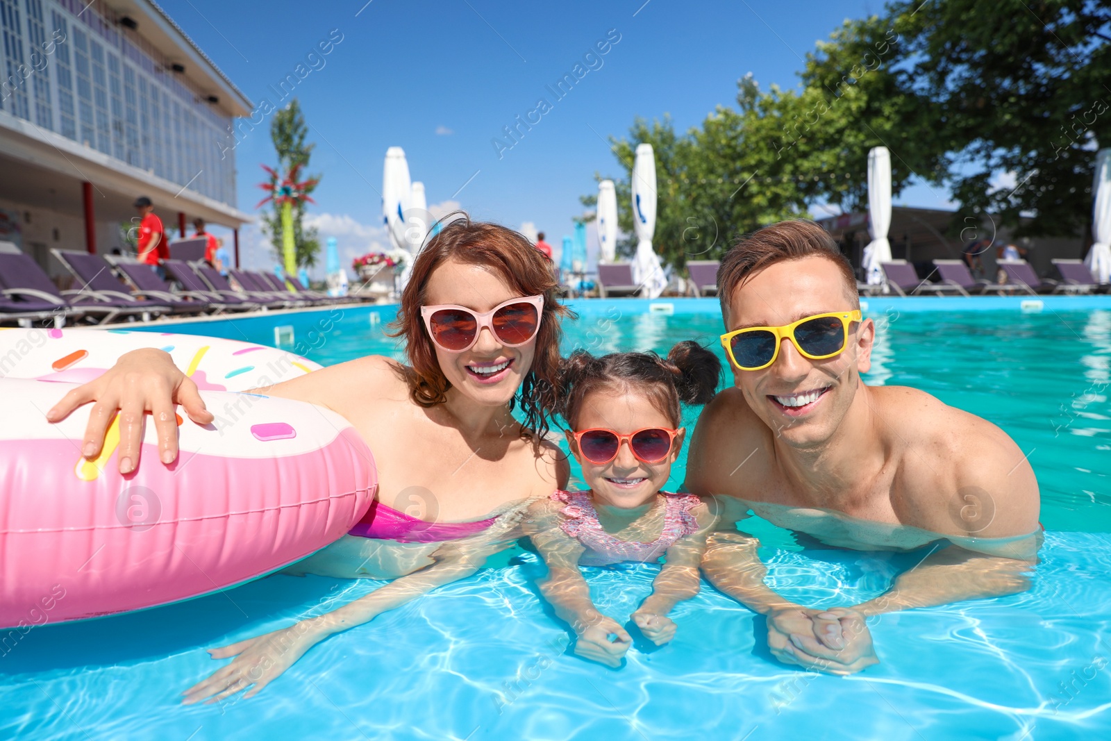 Photo of Happy family in swimming pool at resort