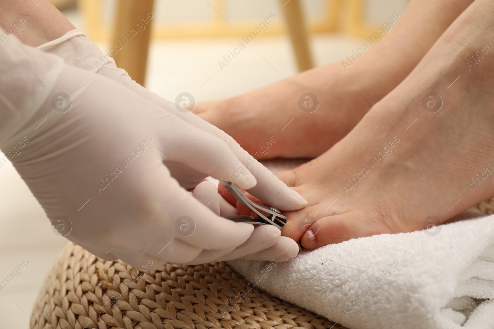 Photo of Professional pedicurist cutting client`s toenails with clipper in beauty salon, closeup