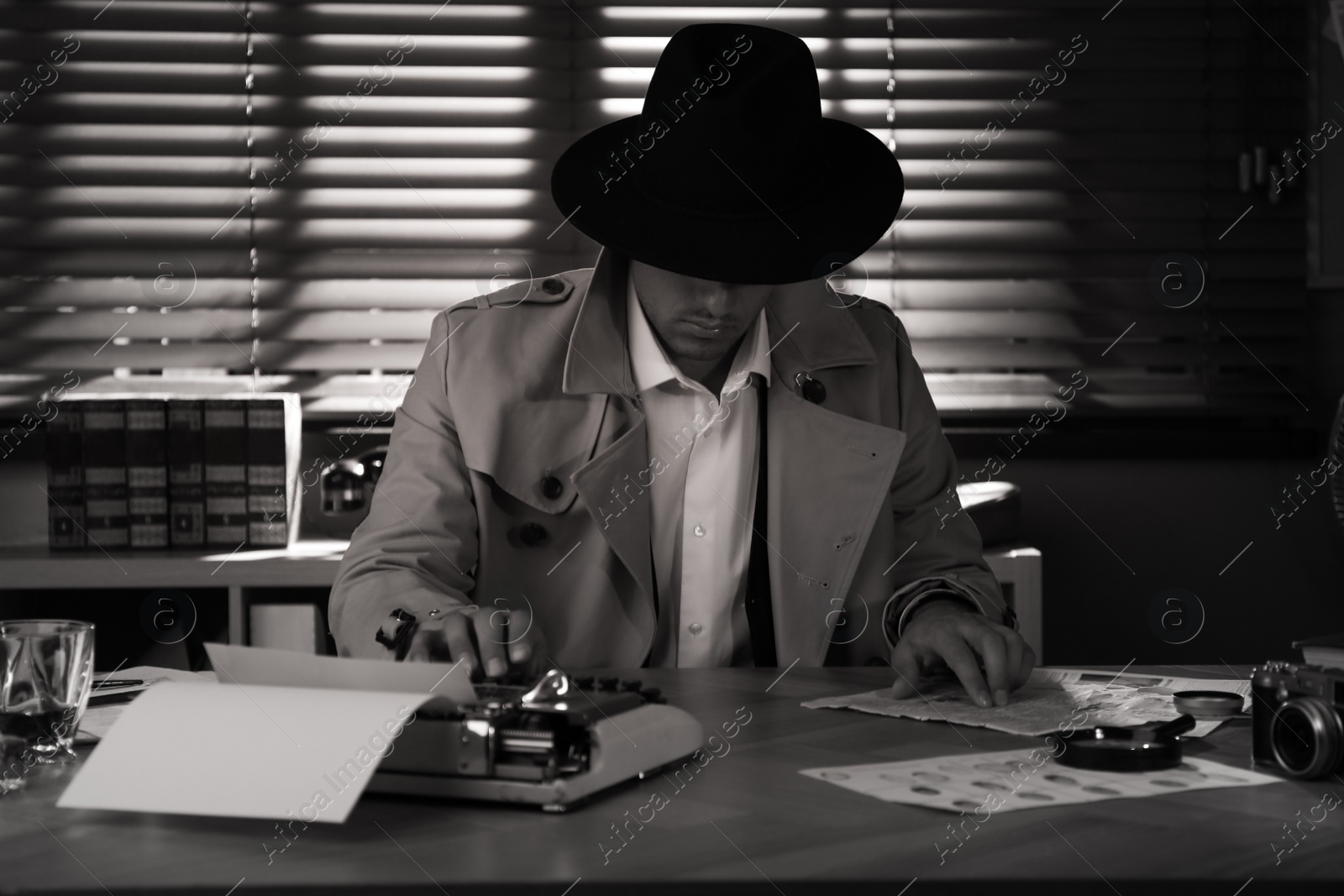 Photo of Old fashioned detective at table in office. Black and white effect