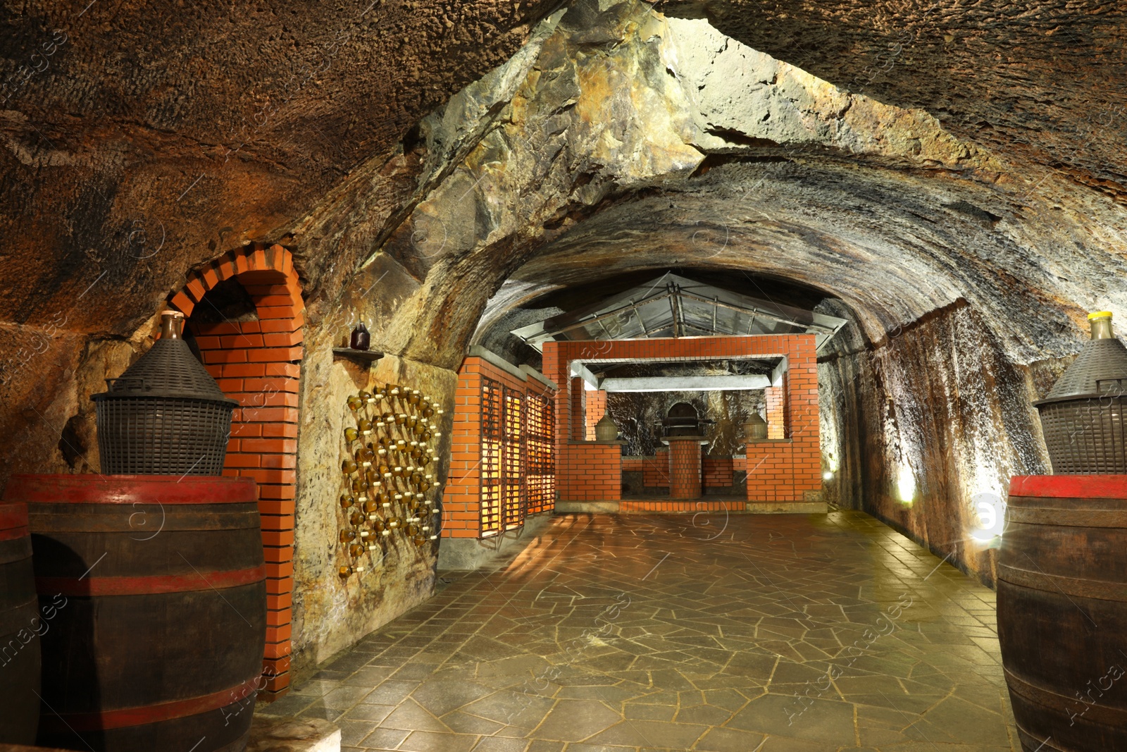 Photo of Beregove, Ukraine - June 23, 2023: Wooden barrels and bottles with alcohol drinks in cellar