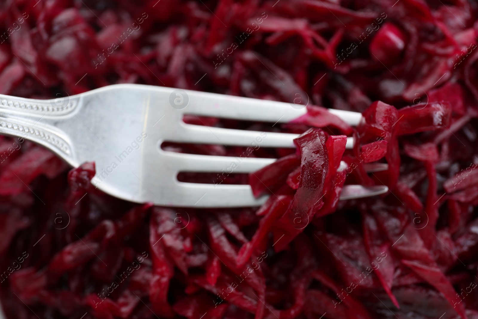 Photo of Fork with tasty red cabbage sauerkraut as background, closeup