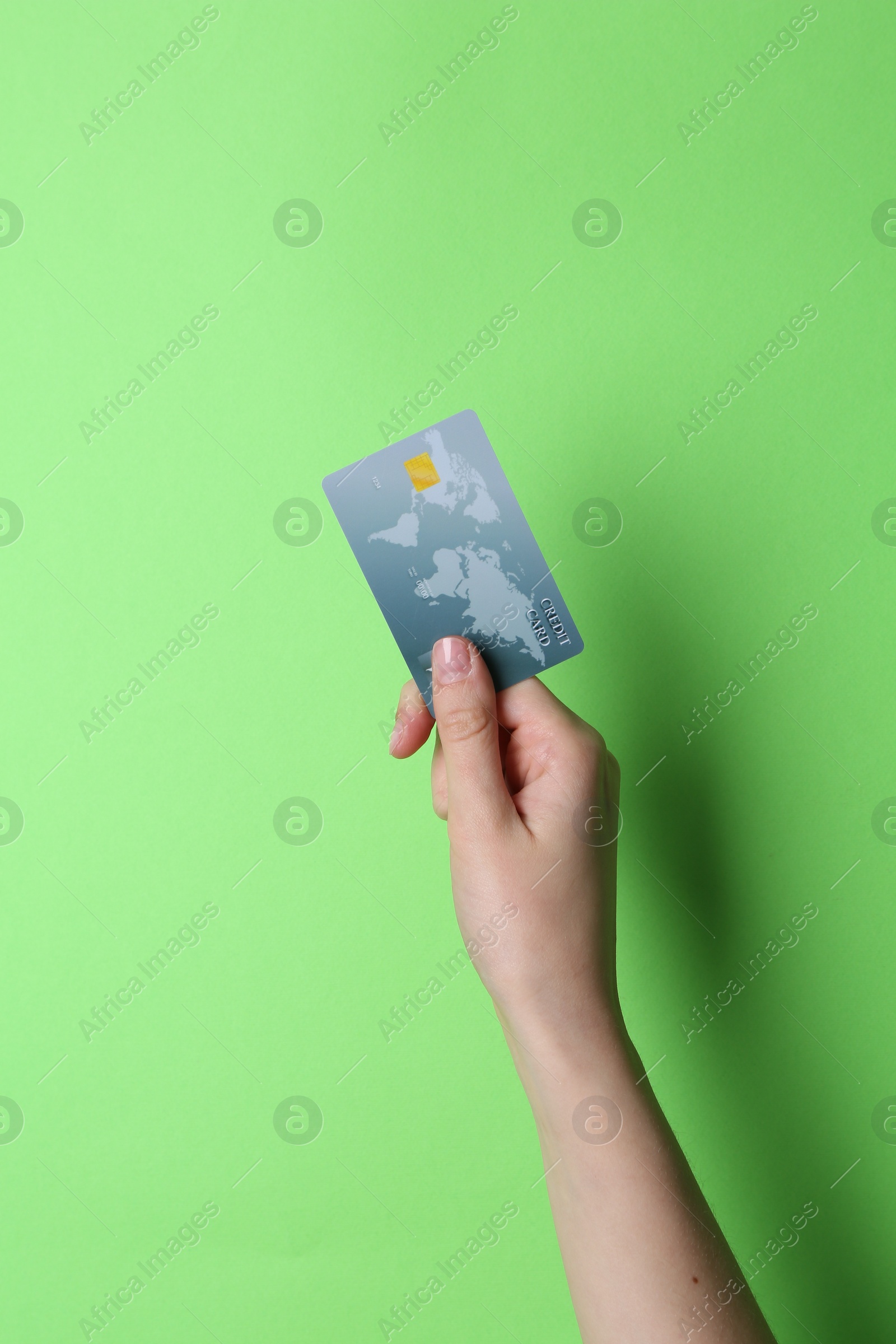 Photo of Woman holding credit card on light green background, closeup