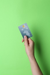 Photo of Woman holding credit card on light green background, closeup