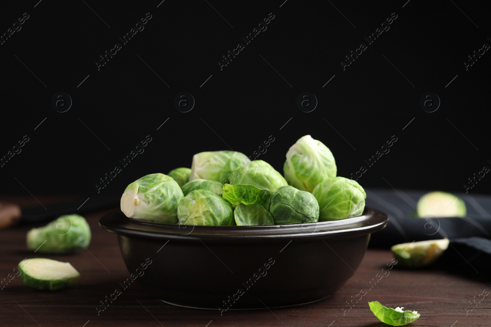 Photo of Bowl with fresh Brussels sprouts on brown wooden table, closeup