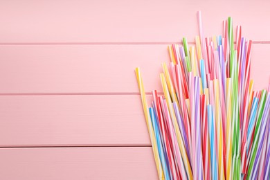 Photo of Colorful plastic drinking straws on pink wooden table, flat lay. Space for text