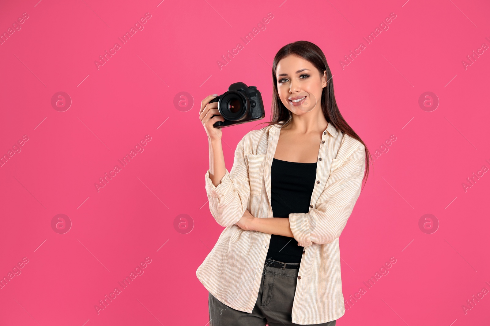 Photo of Professional photographer working on pink background in studio. Space for text