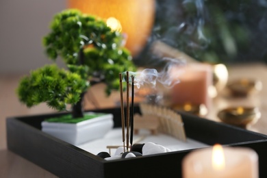 Photo of Miniature zen garden with smoldering incense sticks indoors