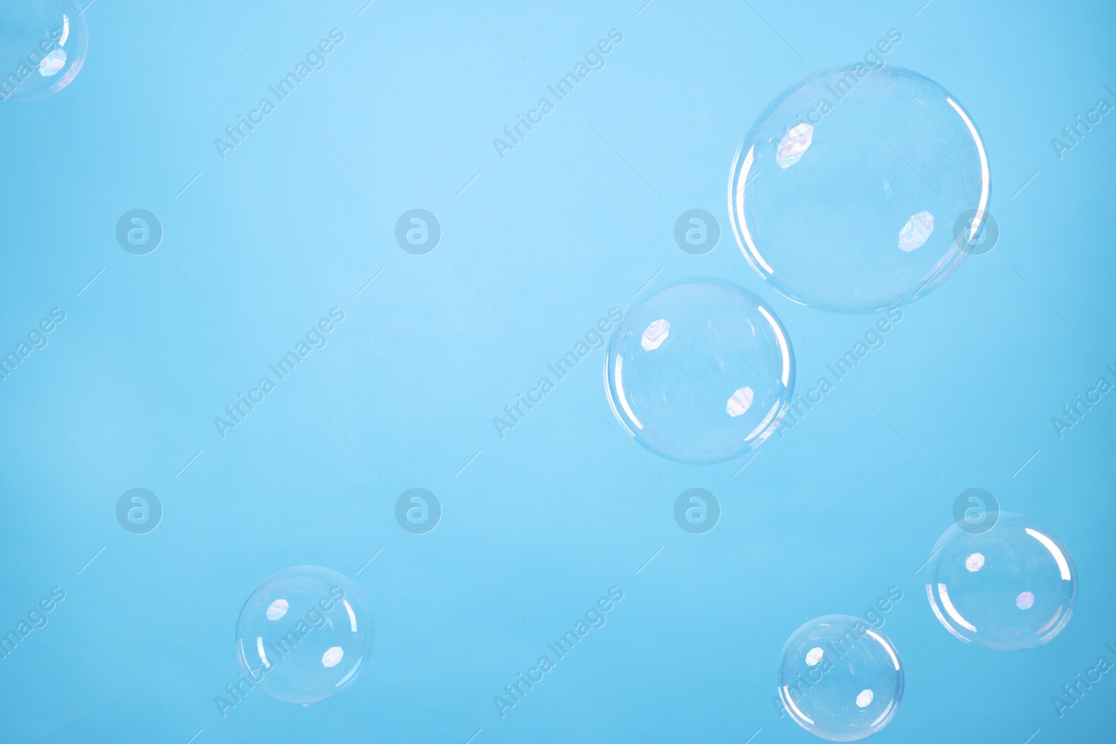 Photo of Many beautiful soap bubbles on light blue background. Space for text