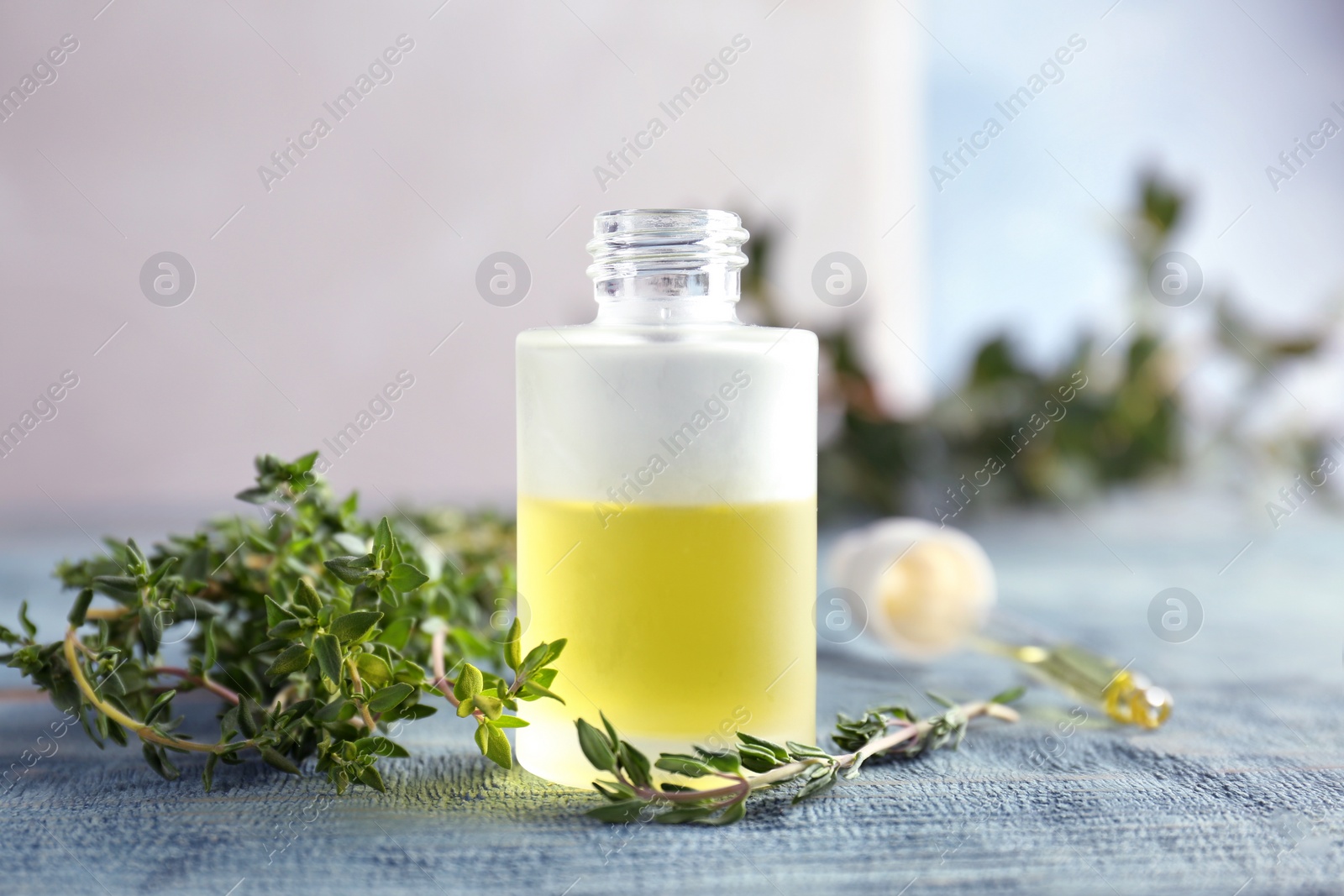 Photo of Bottle of essential oil with thyme on table