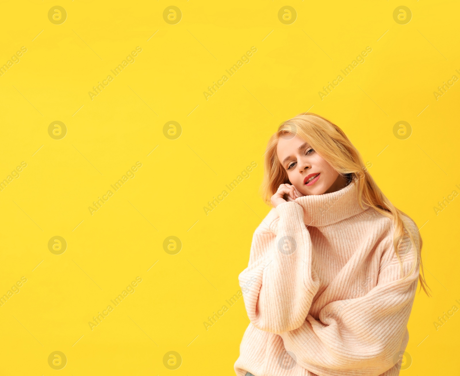Photo of Beautiful young woman wearing warm pink sweater on yellow background. Space for text