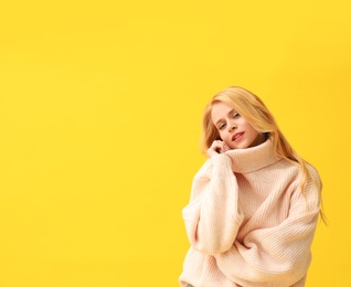 Beautiful young woman wearing warm pink sweater on yellow background. Space for text