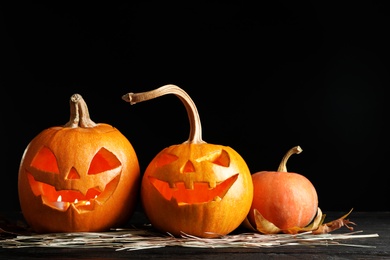 Photo of Halloween pumpkin head jack lanterns on table against dark background