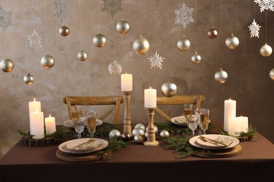 Photo of Christmas table setting with burning candles and festive decor