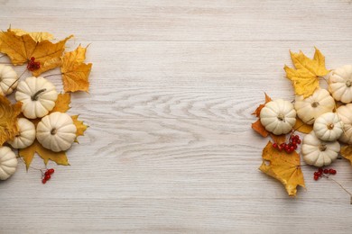 Photo of Dry autumn leaves, berries and pumpkins on light wooden table, flat lay. Space for text