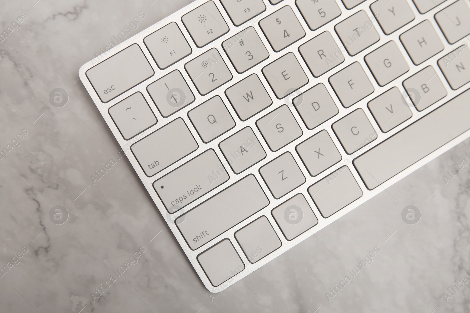 Photo of Internet shopping. Computer keyboard on marble table, top view