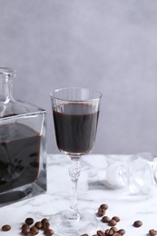 Photo of Coffee liqueur and beans on white marble table, closeup