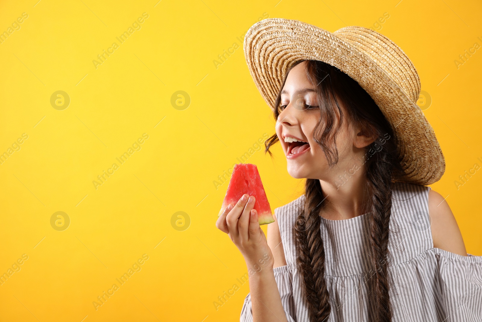 Photo of Cute little girl with watermelon on yellow background. Space for text