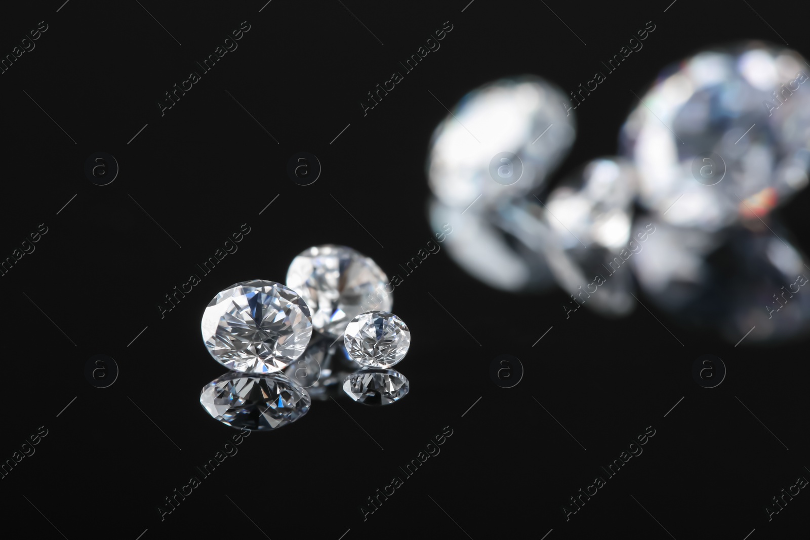 Photo of Beautiful shiny diamonds on black mirror surface, space for text