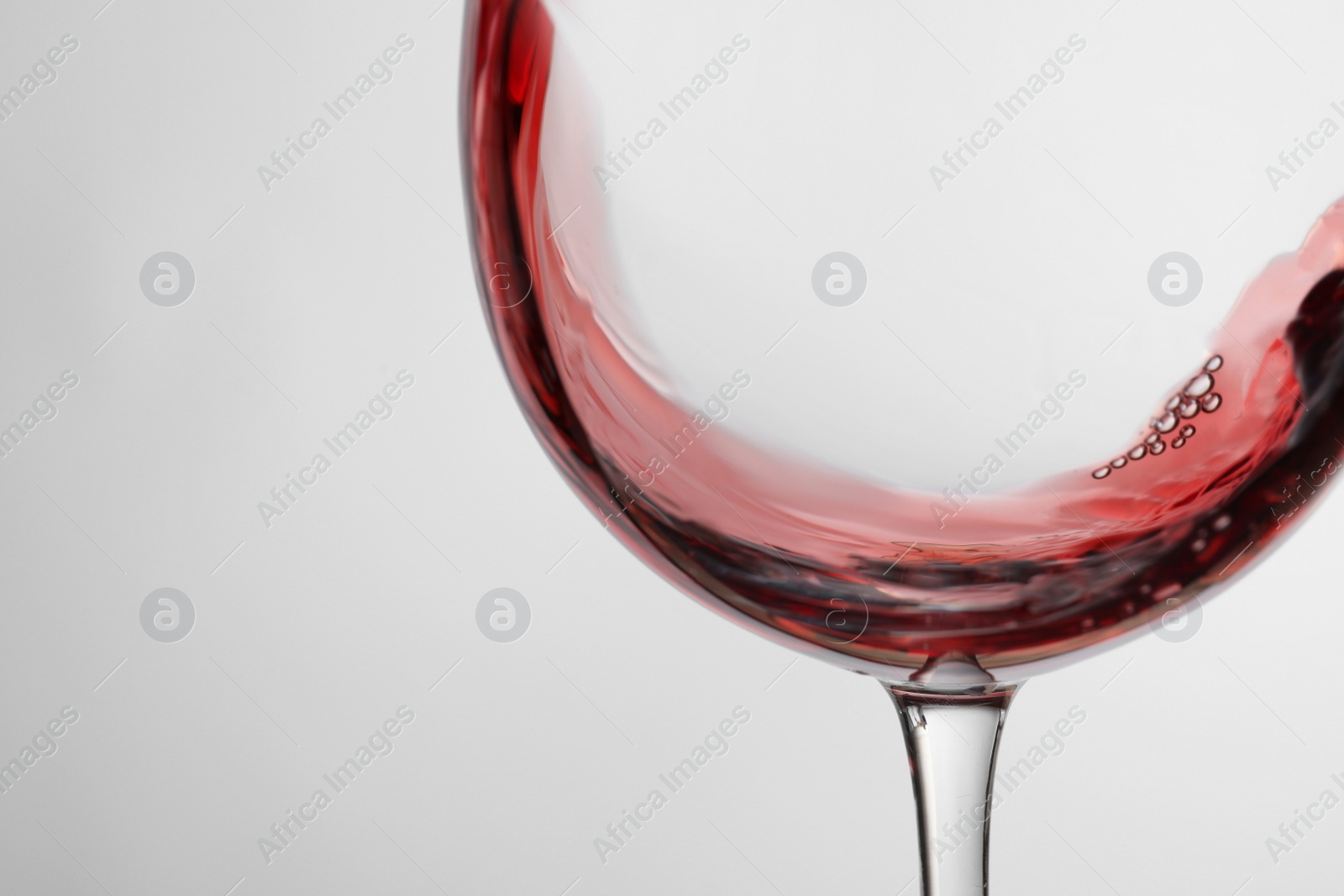 Photo of Pouring red wine into glass on light background, closeup