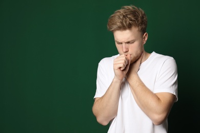 Photo of Handsome young man coughing against color background. Space for text