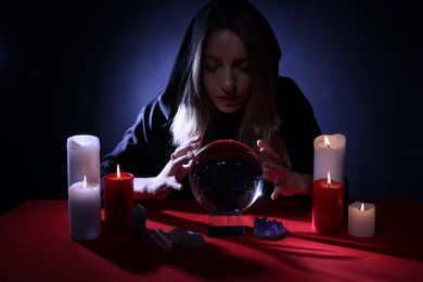 Photo of Soothsayer using crystal ball to predict future at table in darkness. Fortune telling