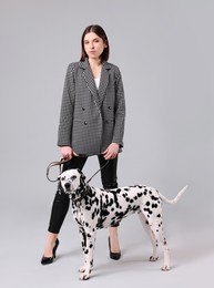 Photo of Beautiful young woman with her adorable Dalmatian dog on light grey background. Lovely pet