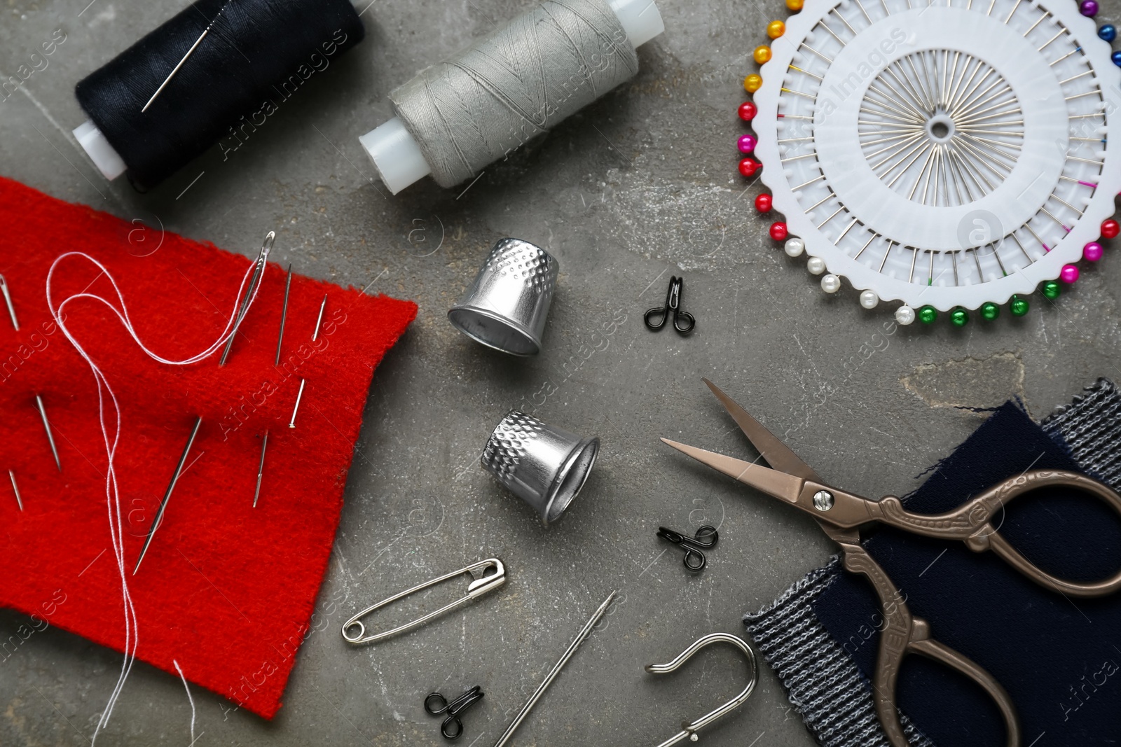 Photo of Flat lay composition with thimbles and different sewing tools on grey table