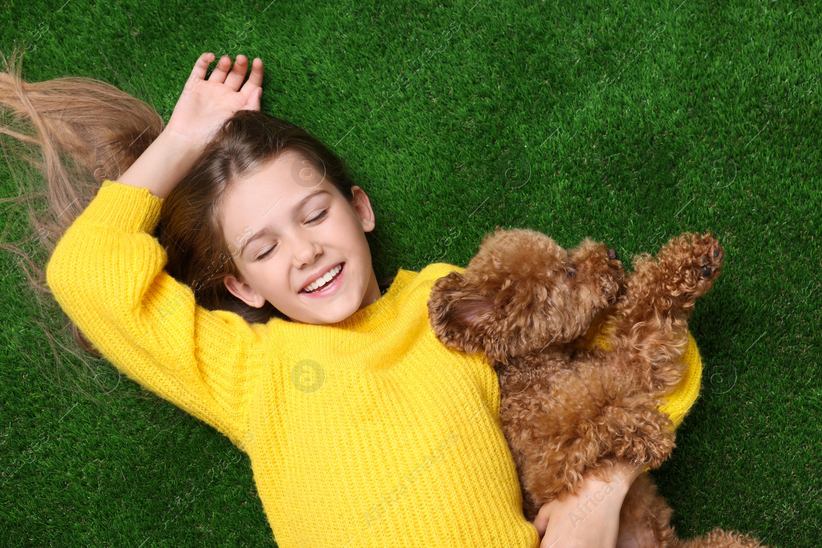 Photo of Little child with cute puppy on green grass, top view. Lovely pet