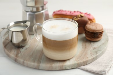 Photo of Aromatic coffee in cup, milk, tasty macarons and eclair on white wooden table