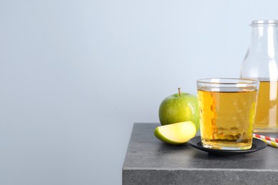 Photo of Fresh juice and apples on grey table. Space for text
