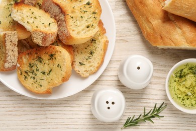 Photo of Tasty baguette with garlic and dill served on white wooden table, flat lay