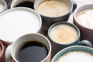 Many different cups with aromatic hot coffee on table, closeup