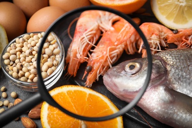 Photo of Different products with magnifier focused on allergenic food, closeup