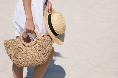 Photo of Woman with beach bag and straw hat on sand, closeup