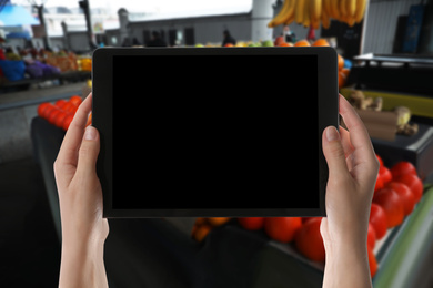 Wholesale trading. Woman using WMS app on tablet at market, closeup 