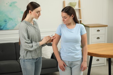 Woman giving insulin injection to her diabetic friend at home