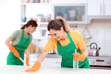 Photo of Team of professional janitors in uniform cleaning kitchen