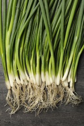 Photo of Fresh green spring onions on black wooden table, flat lay