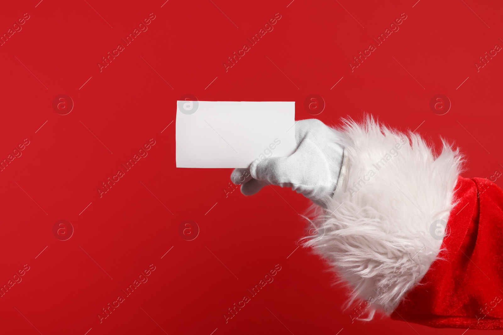 Photo of Merry Christmas. Santa Claus holding blank card on red background, closeup. Space for text