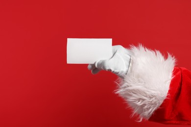 Merry Christmas. Santa Claus holding blank card on red background, closeup. Space for text