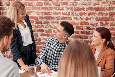 Photo of Businesswoman having meeting with her employees in office. Lady boss