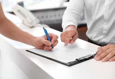 Young man signing documents in car salon