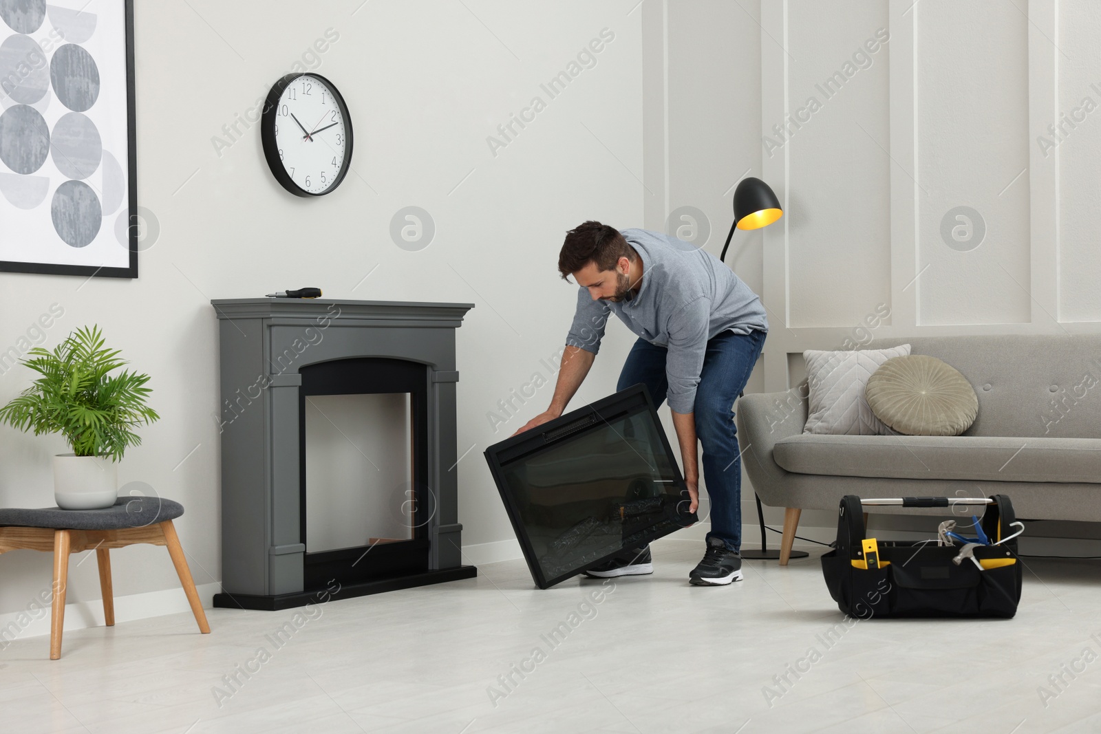 Photo of Man installing electric fireplace near wall in room