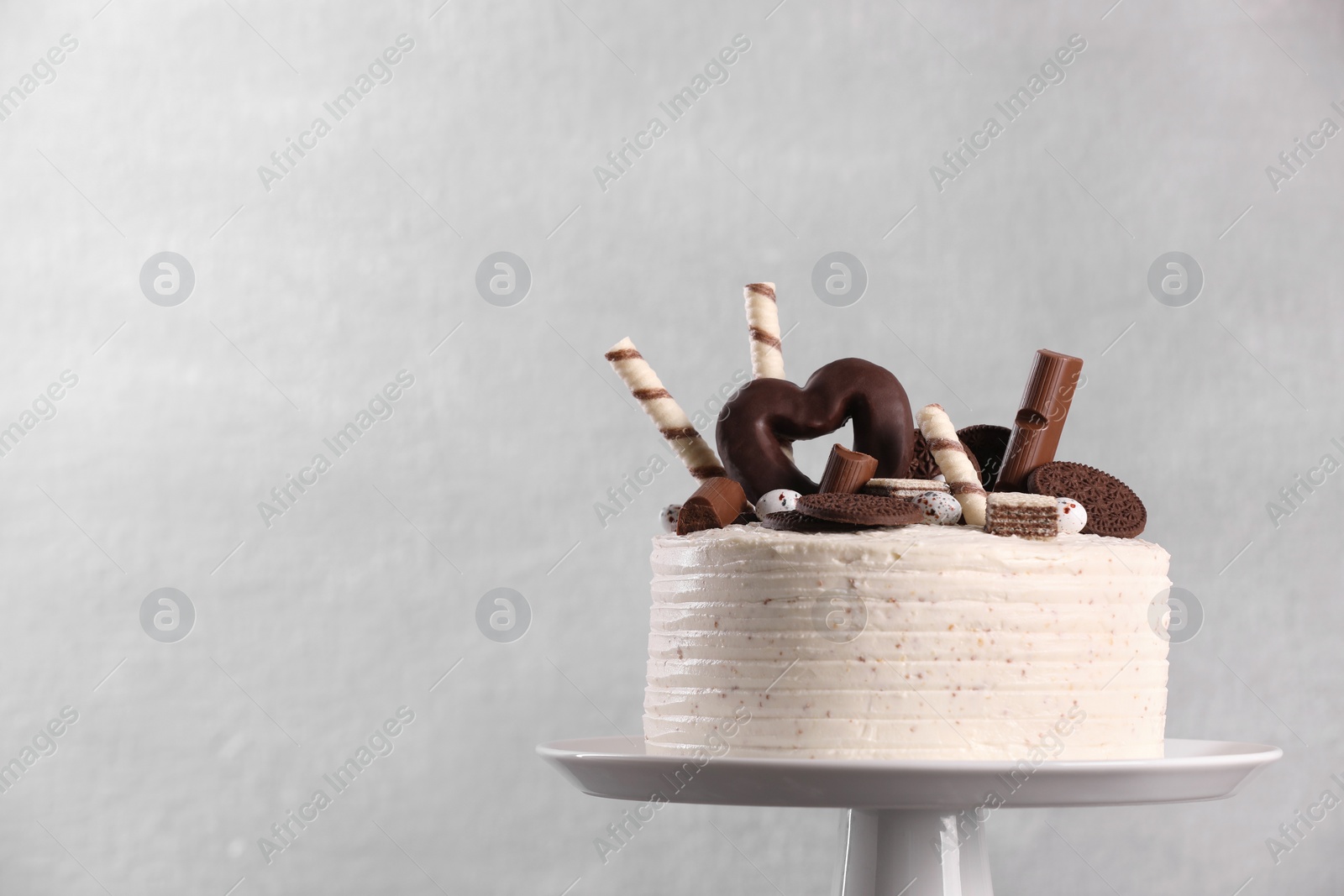 Photo of Delicious cake decorated with sweets on grey background, space for text